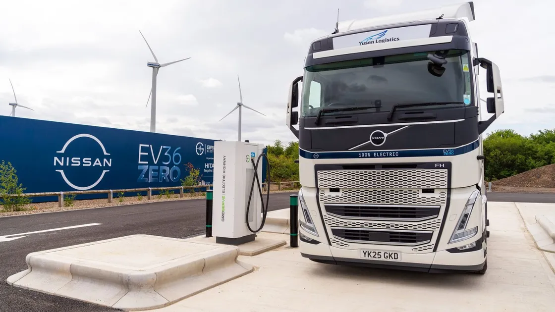 Electric HGV truck at UK depot with charging infrastructure.