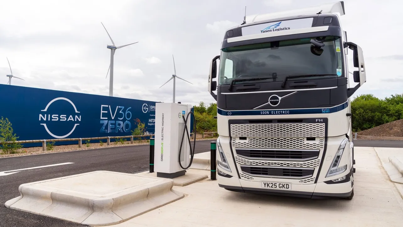 Electric HGV truck at UK depot with charging infrastructure.